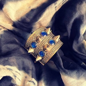 Hinged Kuchi cuff with blue “stones”.