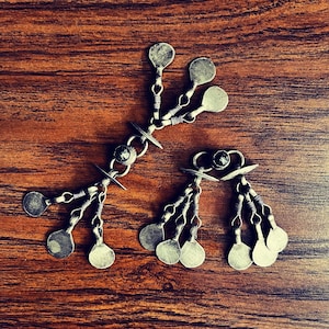 May include: Two silver metal decorative pieces with multiple round charms hanging from each. The charms are connected by small chains and are arranged in a symmetrical pattern.