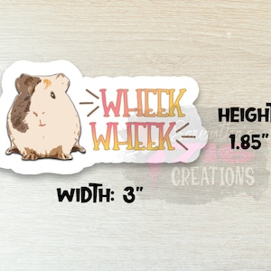 Op de afbeelding: Een witte sticker met een cartoon cavia en de tekst "Wheek Wheek" in roze en geel. De sticker is 3 inch breed en 1,85 inch hoog.