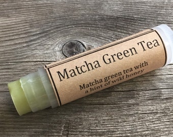 May include: A green lip balm tube with a brown paper label that reads "Matcha Green Tea Matcha green tea with a hint of wild honey".