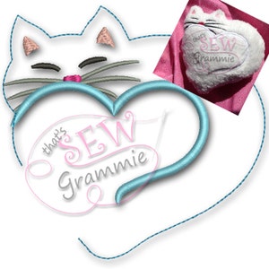 May include: White cat with pink ears and nose sleeping inside a blue heart with the text "that's sew grammie" in pink.