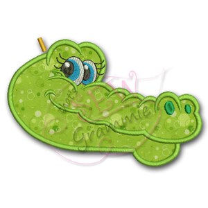 May include: Green alligator applique with a smiling face, big blue eyes, and a green and white polka dot pattern.