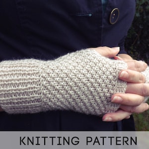 Puede incluir: Un primer plano de un par de guantes sin dedos de punto beige. Los guantes están hechos con un patrón de punto texturizado y los lleva una persona con las manos juntas.