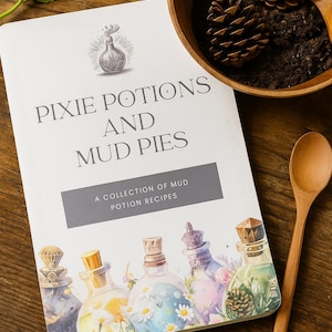 Könnte beinhalten: Ein Buch mit dem Titel "Pixie Potions and Mud Pies" mit Rezepten für Schlamm-Tränke. Das Cover zeigt illustrierte Zaubertränke-Flaschen. Eine Holzschale mit Tannenzapfen und ein Holzlöffel sind ebenfalls vorhanden.