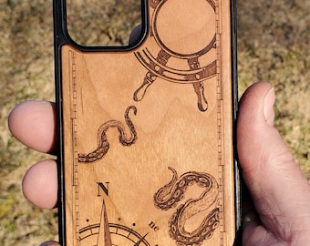May include: A wooden phone case with a black border. The case features a compass, an octopus, and a ship's wheel, all engraved in the wood. The compass has the letters N, E, and NE.