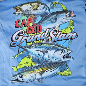 May include: A blue t-shirt with a graphic of four fish and the text "Cape Cod Grand Slam". The fish are a striped bass, a tuna, a bluefish, and a mackerel. The graphic is set against a map of Cape Cod.