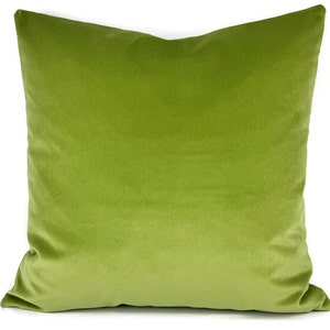 May include: A square, lime green velvet pillow. The pillow is a solid color and has a soft, plush appearance. The pillow is likely used for decorative purposes on a bed or sofa.