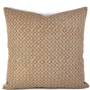 May include: Square decorative pillow with a repeating floral pattern in terracotta and cream. The pillow has a soft, textured appearance and is likely made of fabric. The design is symmetrical and covers the entire surface.