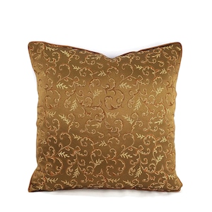 May include: A brown throw pillow with a gold and orange floral pattern.