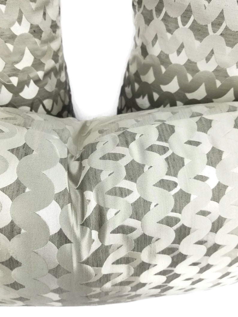 Puede incluir: Dos almohadas decorativas de color blanco roto con un patr&oacute;n tejido de c&iacute;rculos y espirales.