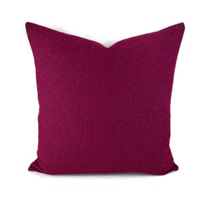 May include: A deep burgundy pillow with a textured fabric. The pillow is square and has a simple design.