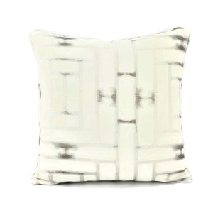 May include: A white throw pillow with a geometric pattern in shades of gray. The pillow is made of a soft, textured fabric.