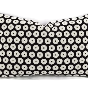 May include: A rectangular throw pillow featuring a repeating geometric pattern of white circular shapes with small square centers arranged in a grid against a solid black background. The pillow has a visible zipper closure along the bottom edge.