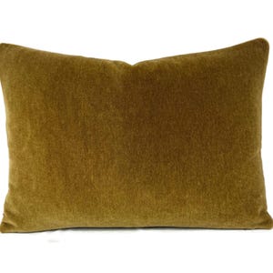 May include: A rectangular decorative pillow in a warm, golden-brown color. The pillow has a soft, velvety texture and is likely made of a plush fabric. The pillow is a solid color and would be suitable for a living room or bedroom.