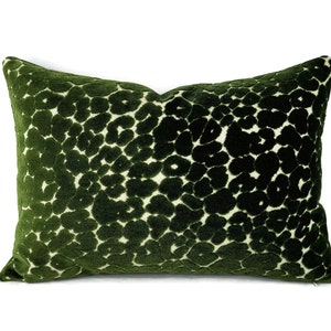 May include: A green velvet pillow with a white abstract pattern. The pillow is soft and plush, and the pattern is subtle and elegant.