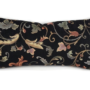 May include: Black rectangular pillow with a floral pattern in shades of brown, green, and orange. The pillow has a subtle sheen and a textured fabric.