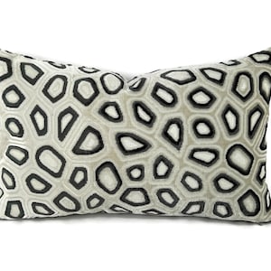 May include: A decorative throw pillow with a geometric pattern of black and white shapes on a beige background.
