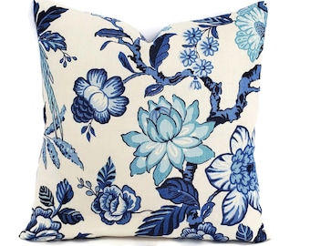 May include: A white pillow with a blue floral pattern. The flowers are in shades of blue and teal, and the stems are dark blue. The pillow is made of a soft, comfortable fabric.