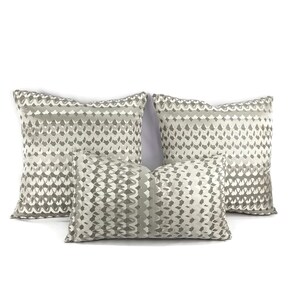 Puede incluir: Tres almohadas decorativas con un patr&oacute;n geom&eacute;trico en tonos grises y blancos.