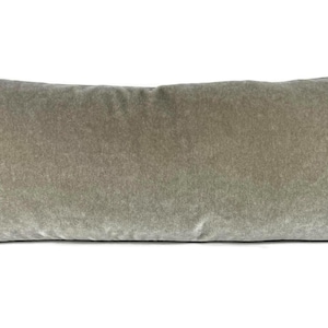 May include: A long, rectangular pillow in a muted sage green color. The pillow has a soft, velvety texture and is approximately 36 inches long. The pillow is a decorative item for a bed or sofa.