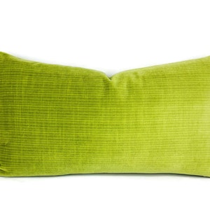 May include: A rectangular, lime green pillow with a textured, corduroy-like surface. The pillow is a solid color and has a soft, plush appearance. The pillow is designed for decorative use on a bed or sofa.