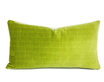 May include: A rectangular, lime green pillow with a textured, corduroy-like surface. The pillow is a solid color and has a soft, plush appearance. The pillow is designed for decorative use on a bed or sofa.