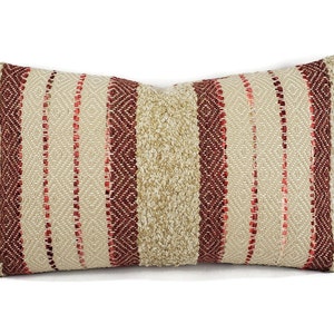 May include: A rectangular pillow with a striped pattern in beige and burgundy. The pillow is made of a woven fabric with a textured surface.