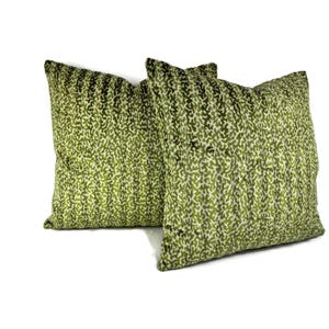 May include: Two green and white patterned throw pillows with a subtle animal print design.