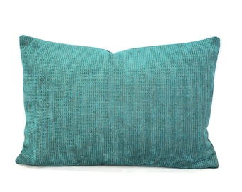 May include: A rectangular teal pillow with a textured, grid-like pattern. The pillow has a soft, plush appearance and is set against a white background. The pillow's color is a vibrant teal with subtle variations in tone.
