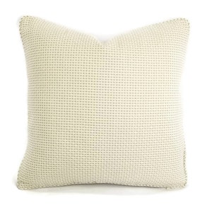 May include: A cream-colored square pillow with a subtle woven texture.