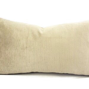 May include: A long, rectangular beige pillow with a subtle ribbed texture. The pillow is made of a soft, plush fabric.