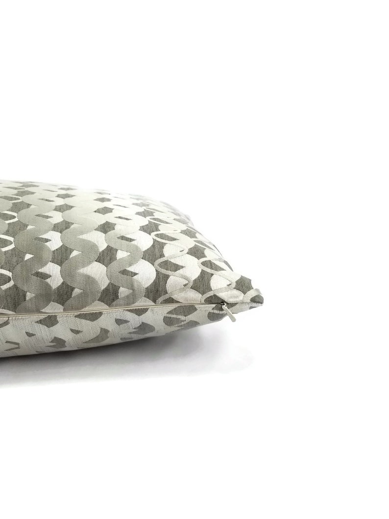 Puede incluir: Una almohada de tiro gris y blanca con cierre de cremallera.