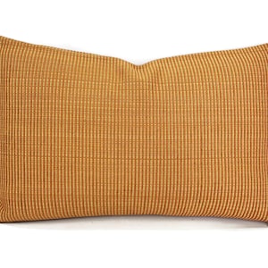 May include: A rectangular throw pillow with a textured, woven fabric in a warm, golden brown color.