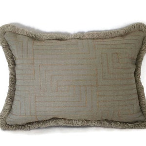 May include: A light gray throw pillow with a geometric pattern and a fringe border.