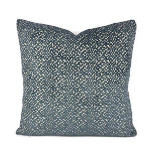 May include: Square decorative pillow with a textured pattern in shades of blue and off-white. The pillow has a soft, inviting appearance, suitable for adding a touch of elegance to any living space. The fabric appears to be woven.