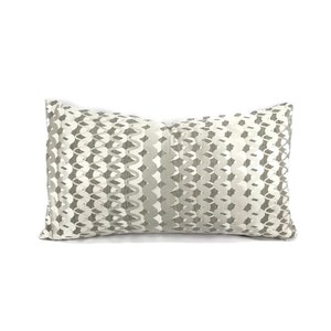 Puede incluir: Una almohada rectangular con fondo blanco y un patr&oacute;n geom&eacute;trico gris. El patr&oacute;n est&aacute; formado por formas repetidas que se asemejan a ondas o cadenas.