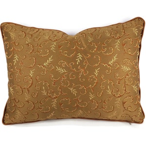 May include: A brown throw pillow with a gold and orange floral pattern.