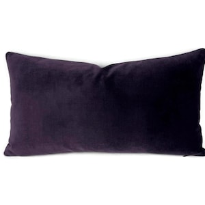May include: A rectangular throw pillow featuring a solid deep purple velvet fabric. The pillow has a smooth, soft-touch texture with a consistent dark violet color across the entire surface and clean, finished edges along the rectangular shape.