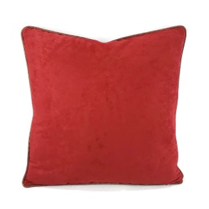 May include: A red square throw pillow with a brown trim.