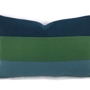 May include: A decorative pillow with a striped pattern in shades of blue and green. The pillow is made of a soft, textured fabric.