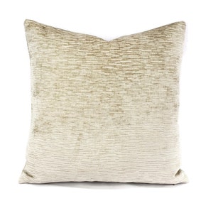 May include: A beige throw pillow with a subtle textured pattern. The pillow is made of a soft, luxurious fabric.
