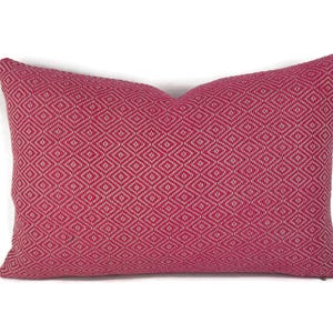 May include: A pink and white diamond patterned throw pillow. The pillow is made of a soft, woven fabric.