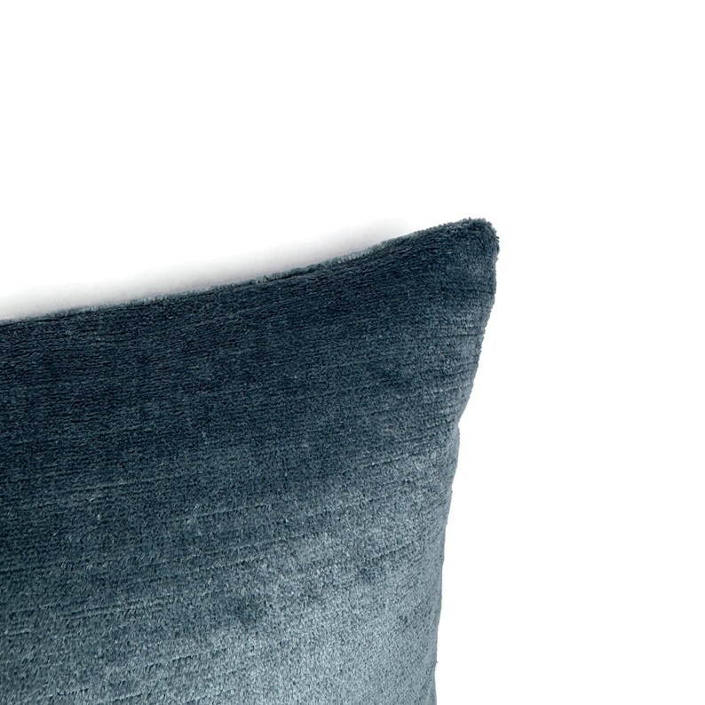 May include: A dark blue throw pillow with a textured, ribbed fabric surface. The pillow features a soft, plush appearance with horizontal lines running across the material, creating a subtle depth and a consistent deep blue color throughout the fabric.