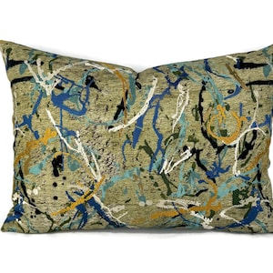 May include: A decorative throw pillow with an abstract design featuring splashes of blue, yellow, green, and black paint on a beige background.