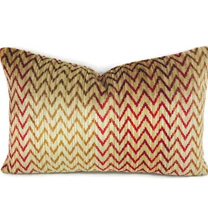 May include: A decorative pillow with a chevron pattern in shades of red, gold, and brown.