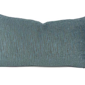 May include: A rectangular throw pillow in a deep teal blue color. The fabric features a textured, raised vertical pattern that creates a subtle wavy effect across the entire surface. The pillow has a structured, rectangular shape with clean edges.