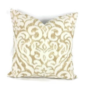May include: A white and beige throw pillow with a damask pattern. The pillow is made of a soft, woven fabric.