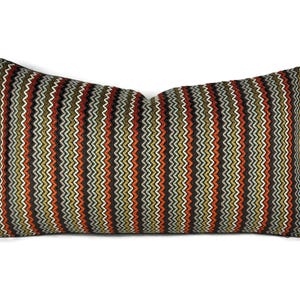 May include: Rectangular decorative pillow with a zig-zag pattern in shades of brown, orange, green, and white. The pillow has a soft, textured appearance and is designed for home decor.