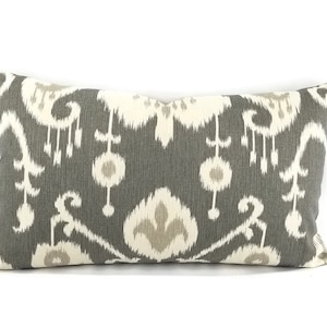 May include: A gray and white patterned lumbar pillow with a geometric design. The pillow is made of a soft, woven fabric.