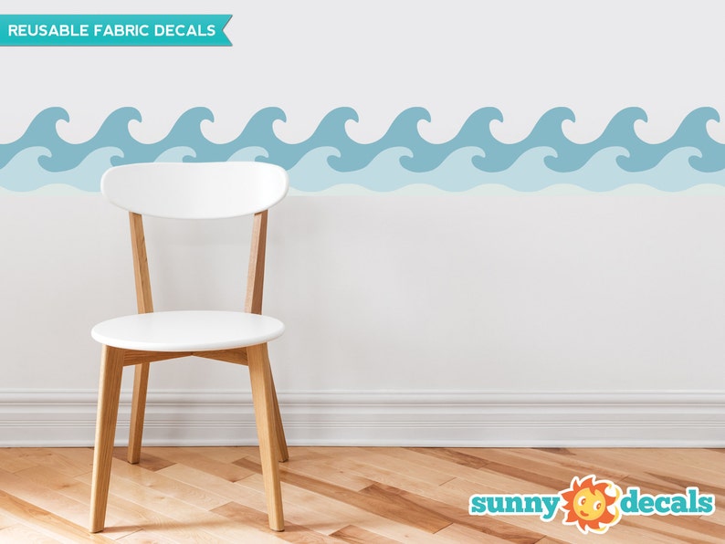 Puede incluir: Calcoman&iacute;as de pared de tela reutilizables con un patr&oacute;n repetitivo de olas azules del oc&eacute;ano. Las calcoman&iacute;as se muestran en una pared blanca con una silla blanca en primer plano. El texto "REUSABLE FABRIC DECALS" es visible en la esquina superior izquierda de la imagen. El texto "sunny decals" es visible en la esquina inferior derecha de la imagen.